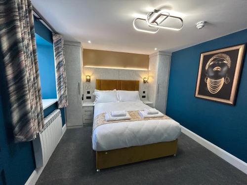 a bedroom with a large bed with a blue wall at Swish Luxury Holiday Apartments in Blackpool