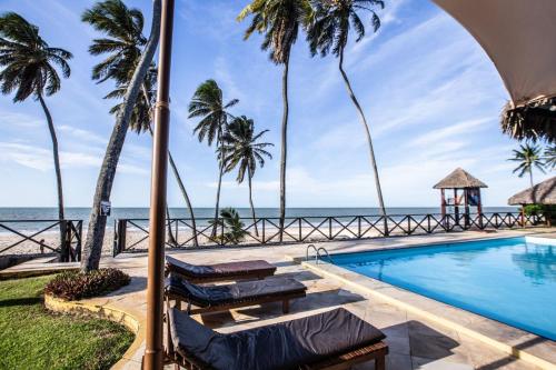 a swimming pool with palm trees and the ocean at FRENTE MAR - Cumbuco - Eco Paradise in Cumbuco