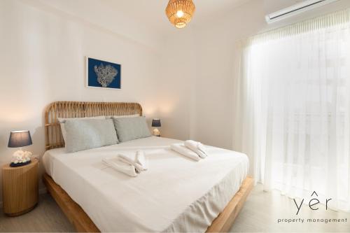 a white bedroom with a large bed with white sheets at Shell-Charm w/Sea View & Parking in Piraeus