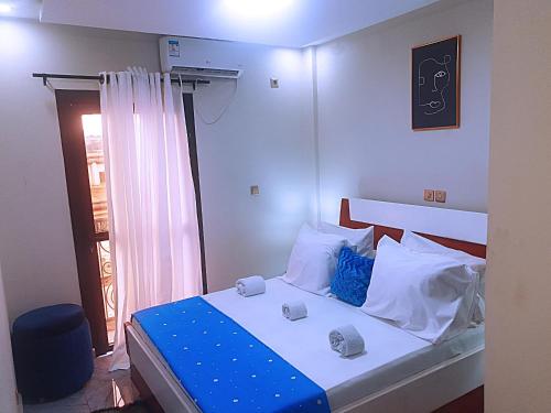 a bedroom with a bed with blue and white pillows at Le meublé des voyageurs in Yaoundé