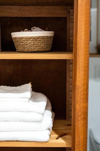 une pile de serviettes sur une étagère avec un panier dans l'établissement La petite madeleine - Chambre d'hôtes & spa, à Burgy
