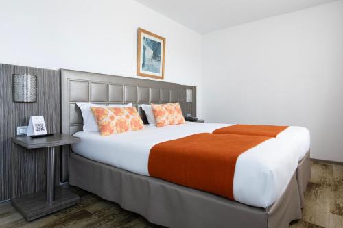 - une chambre avec un grand lit et une couverture orange dans l'établissement Hôtel Atrium, à Arles