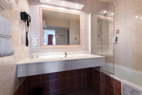 a bathroom with a sink and a shower and a mirror at Hôtel Atrium in Arles