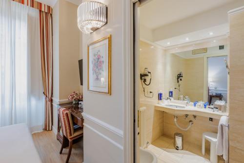La salle de bains est pourvue d'un lavabo et d'un miroir. dans l'établissement FH55 Hotel Calzaiuoli, à Florence