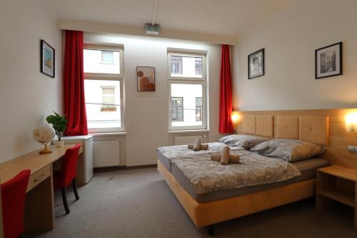 a bedroom with a bed and a desk and two windows at Golden’s Apart-Hotel in Vienna