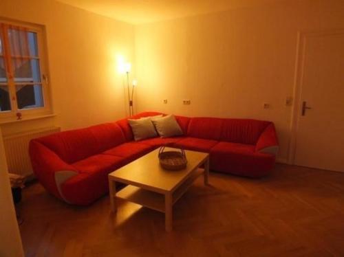 - un canapé rouge dans le salon avec une table dans l'établissement Ferienhaus in OberweißbachThüringer Wald mit Grill und Garten, à Oberweißbach
