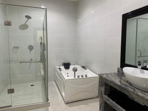 a white bathroom with a shower and a sink at Vinpy hotels in Uyo