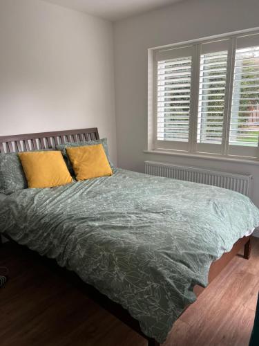 1 Schlafzimmer mit einem Bett mit einer grünen Bettdecke und 2 Fenstern in der Unterkunft 12 Ganderhill in Haywards Heath