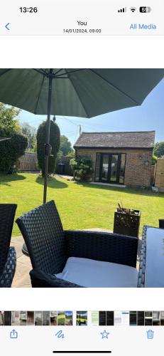 a picture of a patio with an umbrella and chairs at 12 Ganderhill in Haywards Heath