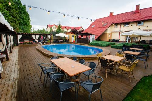 un patio con mesas y sillas junto a una piscina en Hotel Intim, en Rădăuţi