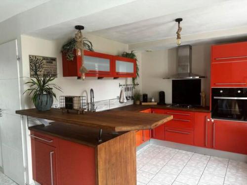 eine Küche mit roten Schränken und einer hölzernen Arbeitsplatte in der Unterkunft Une Parenthèse de Sérénité, séjour avec accès au SPA illimité in Vitré
