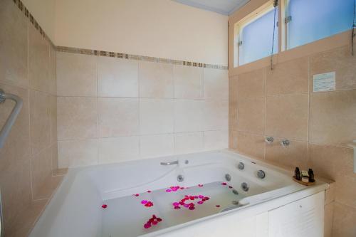 un baño con una bañera con flores rosas. en Pousada Villa Allegra en Tiradentes