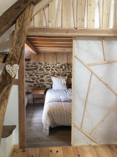 an attic bedroom with a bed and a stone wall at L'AUBERGE DES PYRENEES in La Barthe-de-Neste