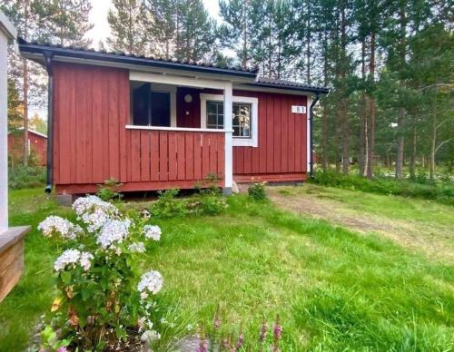 a red tiny house in the middle of a yard at Kleines Ferienhaus auf Naturgrundstück in Seenähe - b48624 in Sollerön