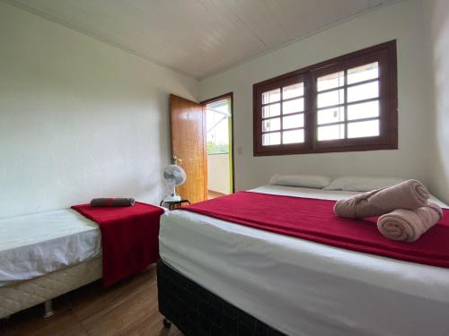 a bedroom with two beds with red sheets and a window at Pousada Vista Serra PRADOS MG in Prados