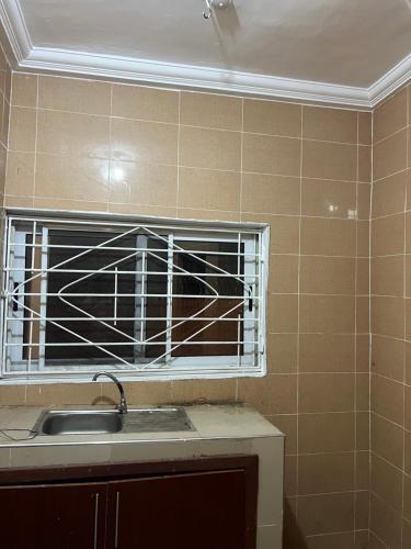 uma cozinha com um lavatório e uma janela em Oyibi Sasaabi Apartment em Lateman