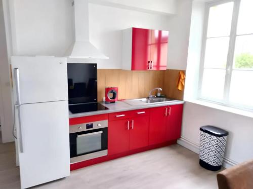 cocina con armarios rojos y nevera blanca en Appartement de 2 chambres avec jardin clos et wifi a Chateaudun, en Châteaudun