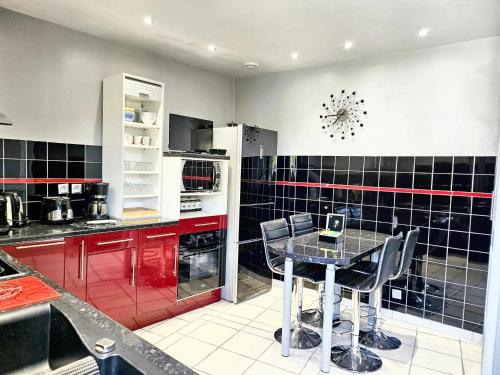 eine Küche mit roten und schwarzen gefliesten Wänden und einem Tisch in der Unterkunft Maison de 2 chambres a Ver sur Mer a 100 m de la plage avec jardin clos et wifi in Ver-sur-Mer