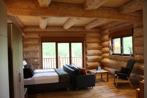 a log cabin bedroom with a bed and a couch at Waldzeit Lodge - Ferienwohnung Hase in NeuhÃ¼tten
