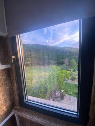 a window with a view of a field and trees at Casinha Pôr do Sol in Aldeia das Dez
