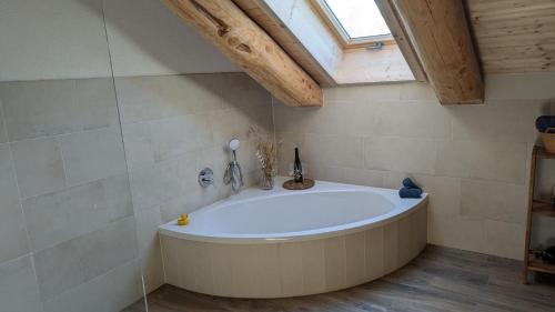 uma grande banheira branca numa casa de banho com uma clarabóia em Waldzeit Lodge - Ferienwohnung Eule em NeuhÃ¼tten
