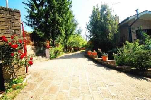 una calle adoquinada en un jardín con árboles y flores en Freistehendes, mitten im Grünen gelegenes Ferienhaus mit privatem Pool, en Manziana