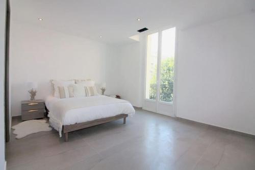 une chambre blanche avec un lit et une grande fenêtre dans l'établissement Unique appartement d'architecte, à Antibes