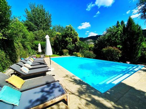 einen Pool mit Chaiselongue und Sonnenschirm in der Unterkunft Studio with lake view shared pool and enclosed garden at Santa Cruz do Douro in Santa Cruz do Douro