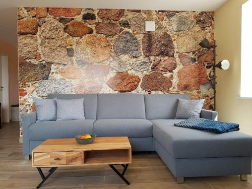 uma sala de estar com um sofá azul e uma parede de pedra em Lindenstuuv em Mittelangeln