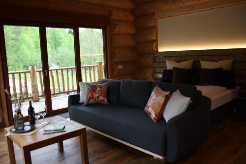a living room with a blue couch in a log cabin at Waldzeit Lodge - Ferienwohnung Fuchs in NeuhÃ¼tten