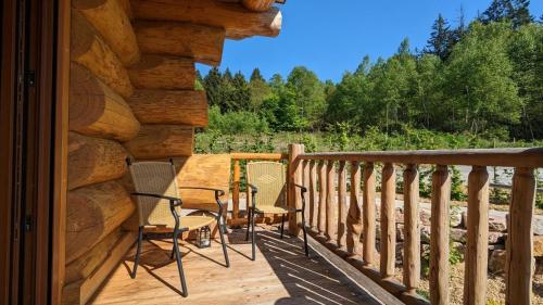 a porch of a log cabin with chairs on it at Waldzeit Lodge - Ferienwohnung Fuchs in NeuhÃ¼tten