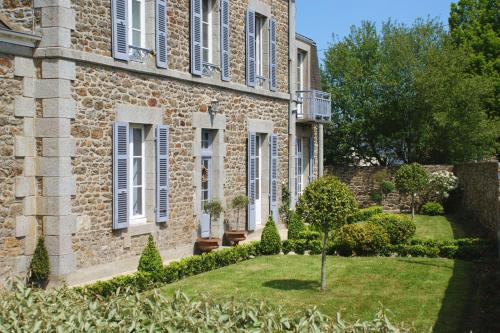 un edificio in pietra con un giardino di fronte di La Gougeonnais a La Richardais