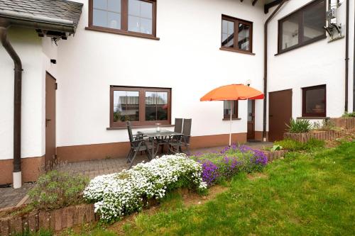 a patio with a table and an umbrella and flowers at Am Tivoli in Hermeskeil