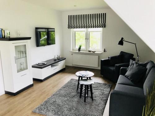 a living room with a black couch and a table at Blinkfüer in Tümlauer Koog