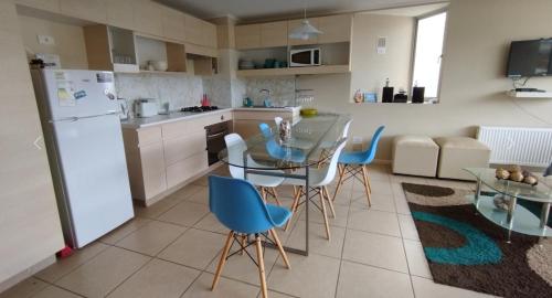 a kitchen with a glass table and blue chairs at Laguna Bahía Mar y Campo in San Antonio