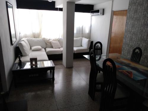 a living room with a white couch and a table at Habitación para una persona in Puerto La Cruz