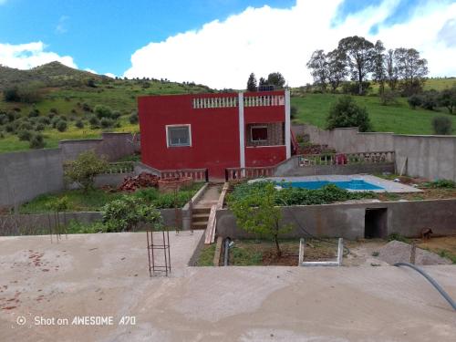 a red house with a pool in front of it at دار الضيافه امال in Tetouan