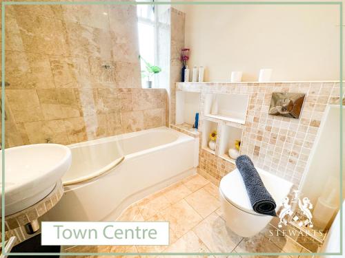 a bathroom with a tub and a toilet and a sink at Town Centre Apartment Sleeps 9 in Bournemouth