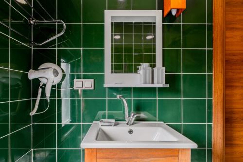 een groene betegelde badkamer met een wastafel en een spiegel bij Marjoram Otel in Sile