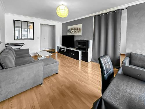 een woonkamer met een bank en een tv bij Le Lumineux - Proche centre-ville et Atlantis in Saint-Herblain