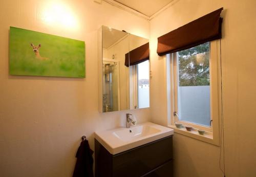 a bathroom with a sink and a mirror and a window at Large, central and quiet apartment. in Stavanger