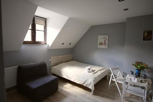 a bedroom with a bed and a chair and a window at Pokoje Nadrzeczna 45 in Kazimierz Dolny