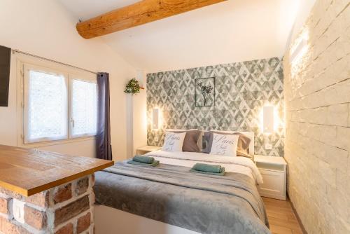 a bedroom with a bed and a brick wall at La Petite Maison in Bédoin