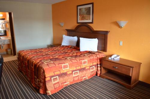 Habitación de hotel con cama y mesita de noche en Royal Inn Greenville, en Greenville