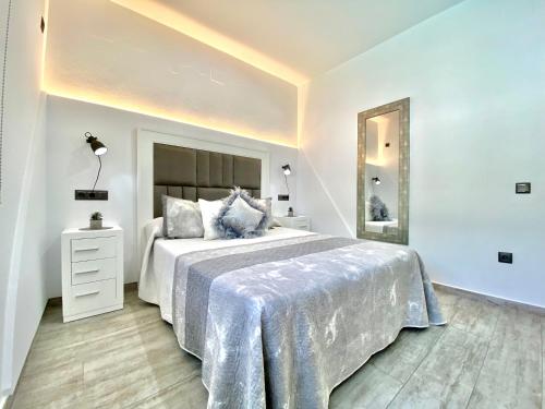 a white bedroom with a large bed and a mirror at Villa MARABÚ,piscina privada en Conil de la Frontera in Conil de la Frontera