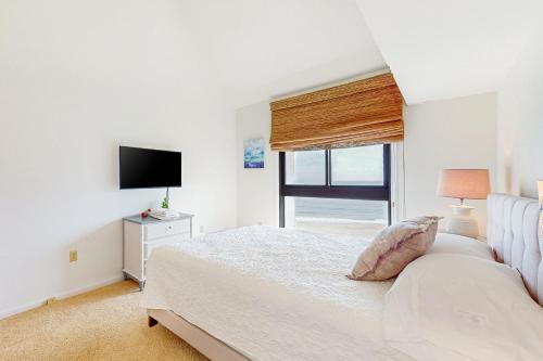 a white bedroom with a bed and a television at Sea Colony - 902 Georgetowne House in Bethany Beach