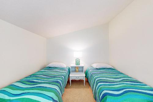 two twin beds in a room with a table at Sea Colony - 902 Georgetowne House in Bethany Beach