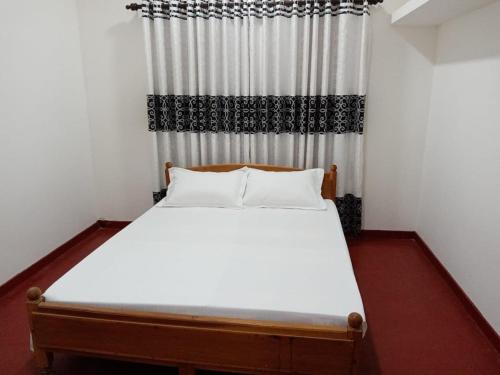 a bedroom with a white bed with a curtain at Whiterock Villa in Urelu