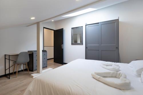 une chambre avec un grand lit blanc et un bureau dans l'établissement Le Havre Tervillois, à Terville