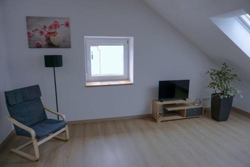 Sala de estar blanca con silla y TV en Ferienwohnung Ottobeuren, en Ottobeuren